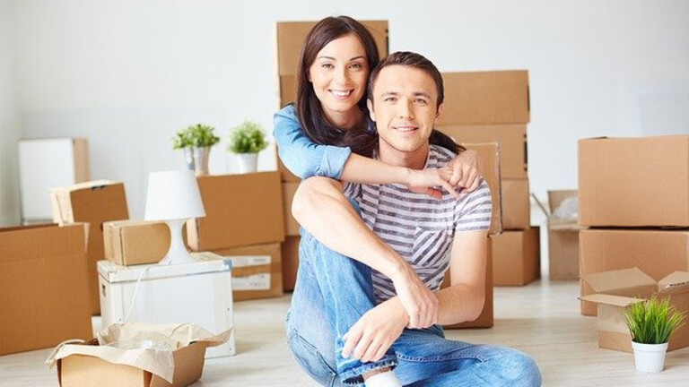 Kaufberatung Glückliches Paar nach erfolgreicher Immobilienkaufberatung im neuen Zuhause mit Umzugskartons